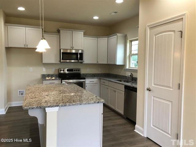 kitchen featuring appliances with stainless steel finishes, a center island, white cabinets, and decorative light fixtures