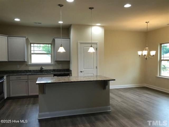 kitchen with stone counters, a kitchen island, and pendant lighting