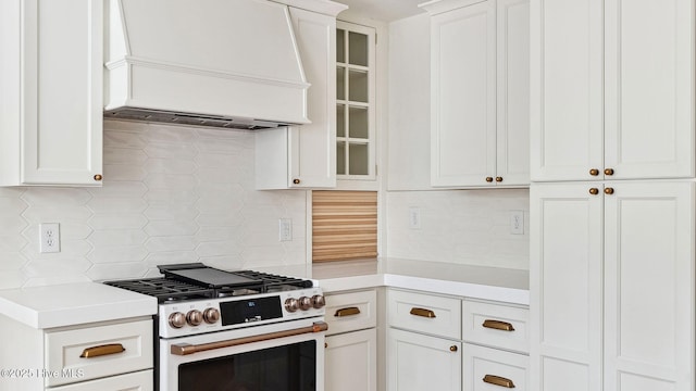 kitchen featuring tasteful backsplash, white gas range, white cabinetry, and custom exhaust hood