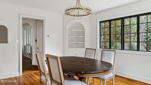 dining room with a wealth of natural light, ornamental molding, hardwood / wood-style floors, and a chandelier