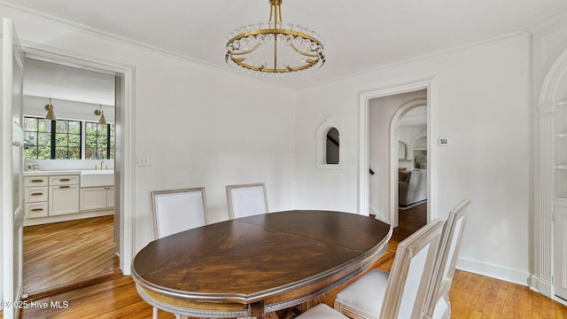 dining area featuring sink, crown molding, and light wood-type flooring