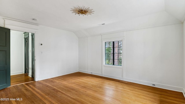 spare room featuring hardwood / wood-style flooring and vaulted ceiling