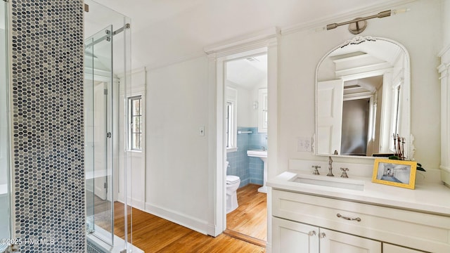 bathroom featuring toilet, an enclosed shower, wood-type flooring, tile walls, and vanity