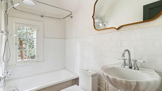 full bathroom with sink, tile walls, washtub / shower combination, and toilet