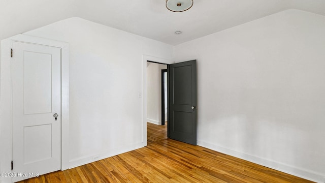 unfurnished bedroom with vaulted ceiling and hardwood / wood-style floors