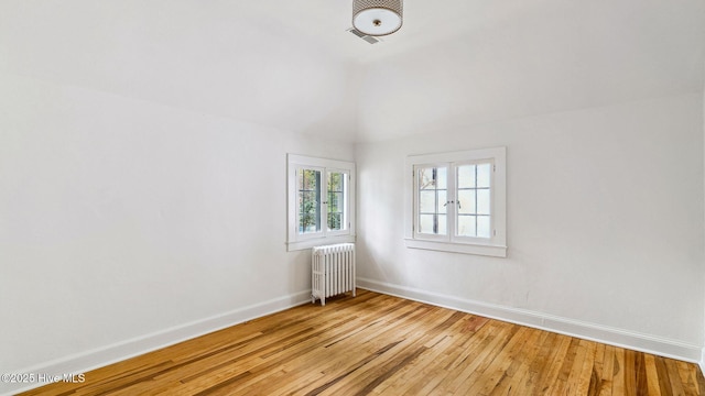 spare room featuring radiator heating unit and light hardwood / wood-style floors