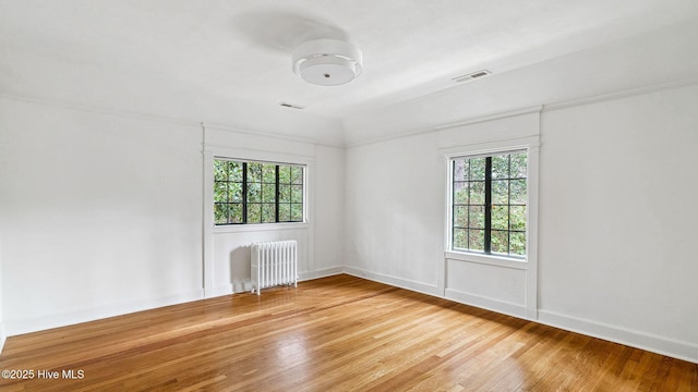 spare room with lofted ceiling, radiator, plenty of natural light, and hardwood / wood-style floors