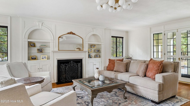 living room featuring an inviting chandelier, built in shelves, and wood-type flooring