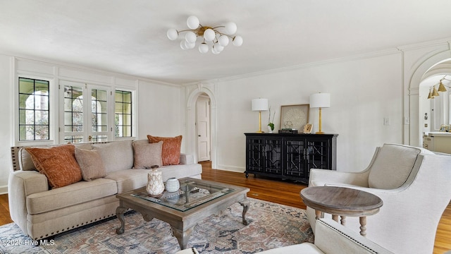 living room with wood-type flooring, ornamental molding, and a chandelier