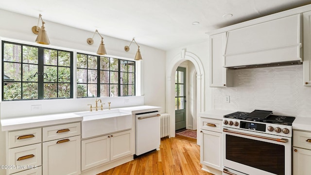 kitchen with radiator heating unit, sink, dishwashing machine, backsplash, and white gas range oven