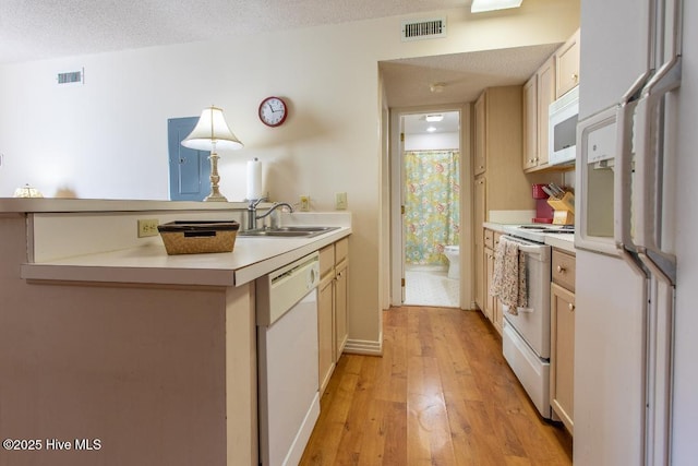 kitchen with sink, a textured ceiling, light hardwood / wood-style flooring, kitchen peninsula, and white appliances