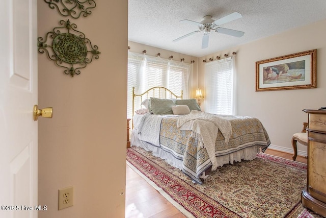 bedroom with ceiling fan, light hardwood / wood-style floors, and a textured ceiling