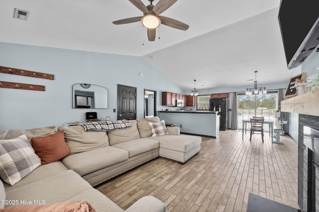 living room with ceiling fan with notable chandelier and high vaulted ceiling