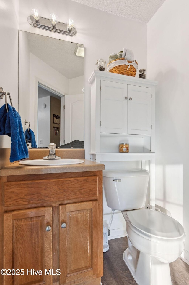 bathroom featuring hardwood / wood-style flooring, vanity, toilet, and a textured ceiling