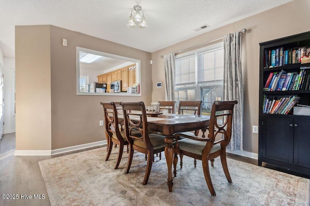 dining room with a textured ceiling and light hardwood / wood-style floors