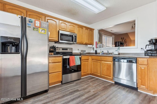 kitchen with sink, dark wood-type flooring, stainless steel appliances, and a textured ceiling