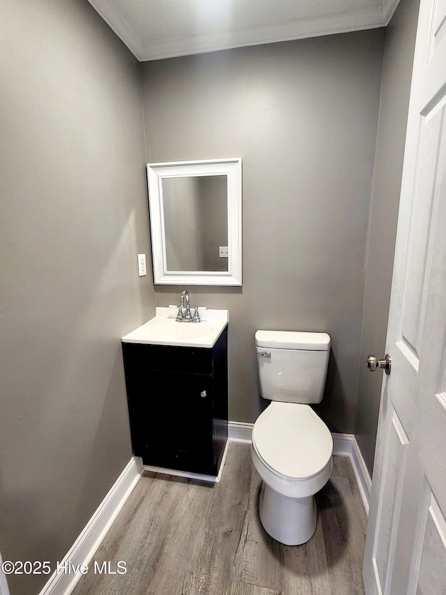 bathroom featuring vanity, hardwood / wood-style flooring, crown molding, and toilet