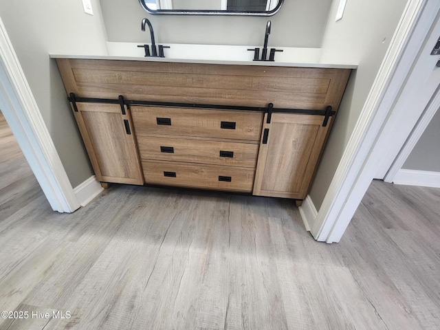 interior space with a barn door, sink, and light wood-type flooring