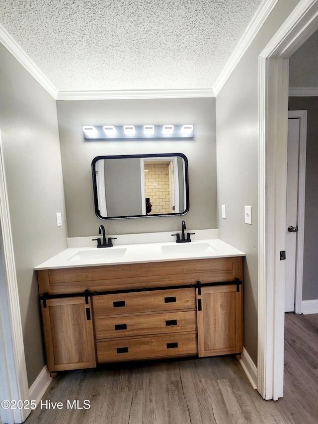 bathroom with hardwood / wood-style flooring, vanity, crown molding, and a textured ceiling