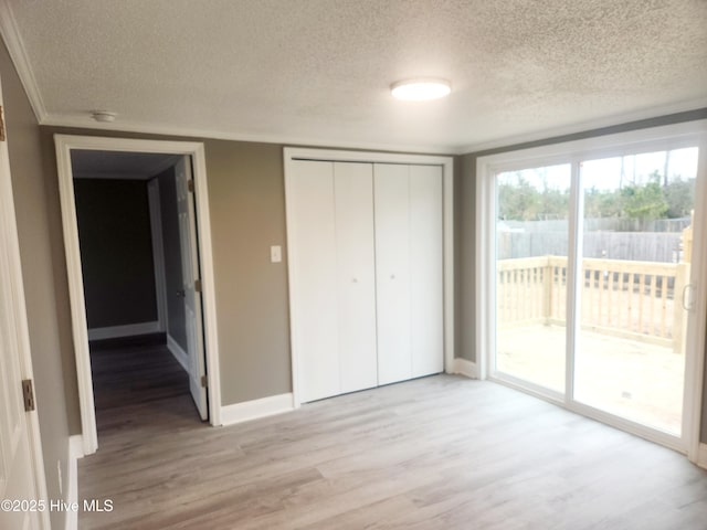 unfurnished bedroom featuring access to exterior, a closet, a textured ceiling, and light wood-type flooring