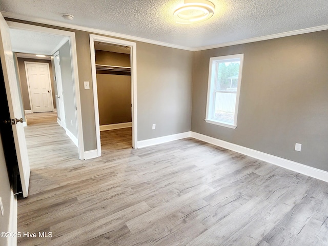 unfurnished bedroom with crown molding, a textured ceiling, a closet, and light hardwood / wood-style flooring