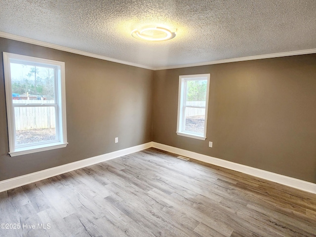 unfurnished room with crown molding, a wealth of natural light, and light hardwood / wood-style floors