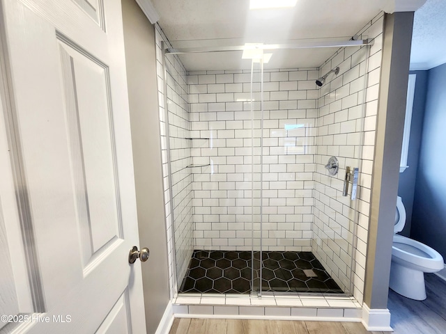 bathroom with a shower with door, hardwood / wood-style floors, and toilet