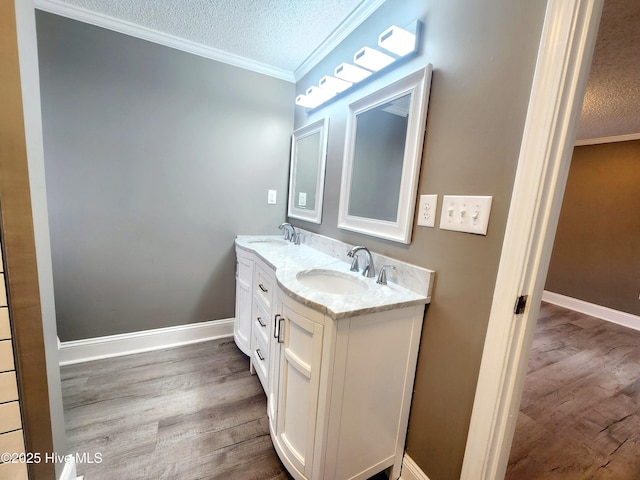 bathroom with crown molding, hardwood / wood-style floors, vanity, and a textured ceiling