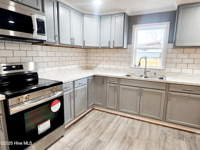 kitchen featuring stainless steel appliances, sink, gray cabinetry, and light hardwood / wood-style flooring