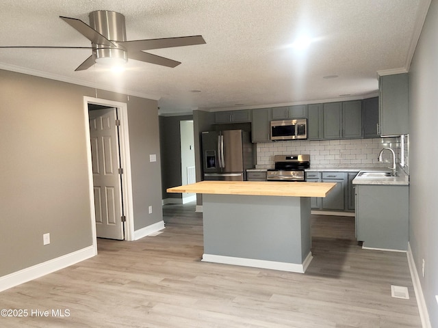 kitchen with wood counters, stainless steel appliances, sink, and ornamental molding