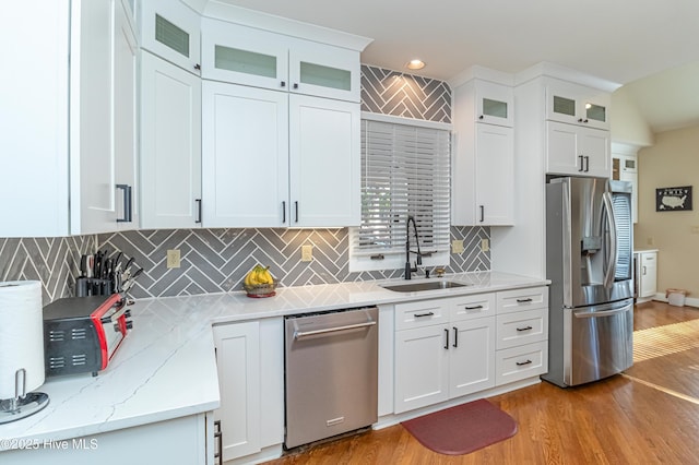 kitchen with sink, stainless steel appliances, white cabinets, and light wood-type flooring