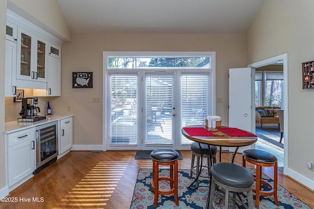 dining space with wine cooler, a healthy amount of sunlight, bar, and lofted ceiling