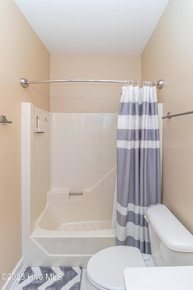 bathroom with toilet and shower / bath combo with shower curtain