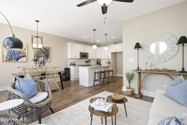 living room featuring sink, ceiling fan with notable chandelier, and dark hardwood / wood-style flooring