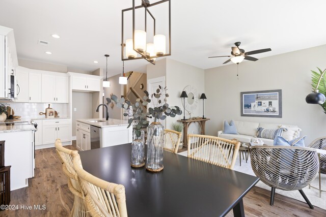 dining space featuring sink, ceiling fan with notable chandelier, and dark wood-type flooring