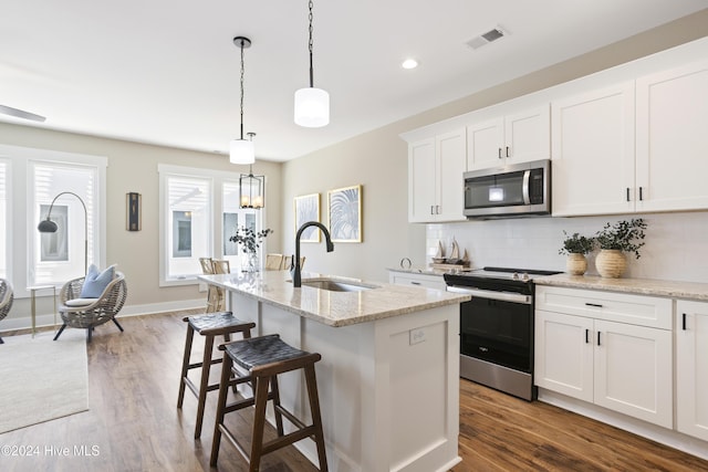 kitchen featuring sink, white cabinetry, stainless steel appliances, a kitchen island with sink, and backsplash