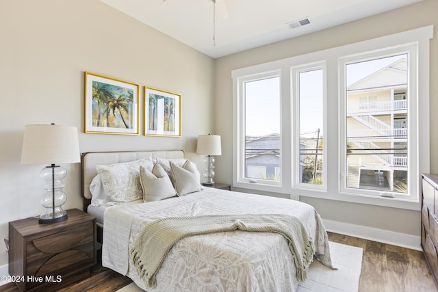 bedroom with multiple windows, dark hardwood / wood-style floors, and ceiling fan