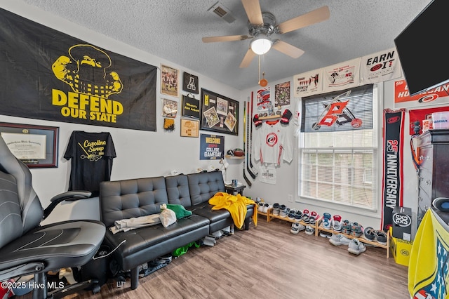 workout room with wood-type flooring, ceiling fan, and a textured ceiling