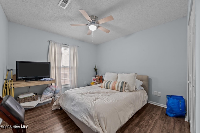 bedroom featuring ceiling fan, dark hardwood / wood-style floors, and a textured ceiling