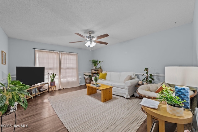 living room with hardwood / wood-style flooring, ceiling fan, and a textured ceiling