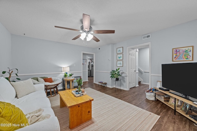 living room with dark wood-type flooring, a textured ceiling, and ceiling fan