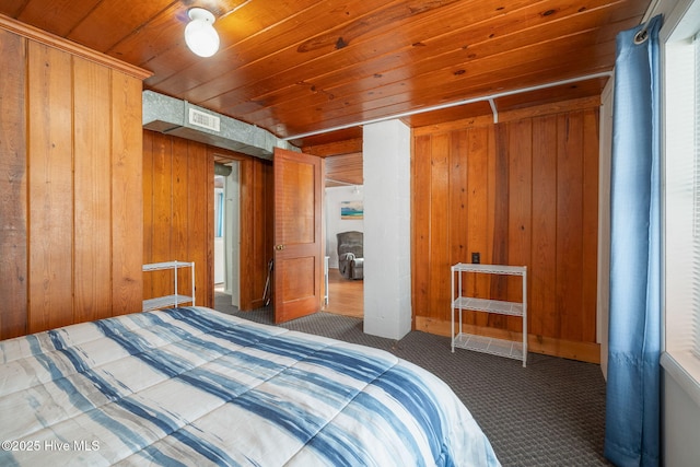 carpeted bedroom with wooden ceiling and wood walls