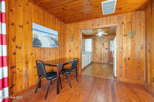 dining space with hardwood / wood-style floors, wooden walls, and wooden ceiling