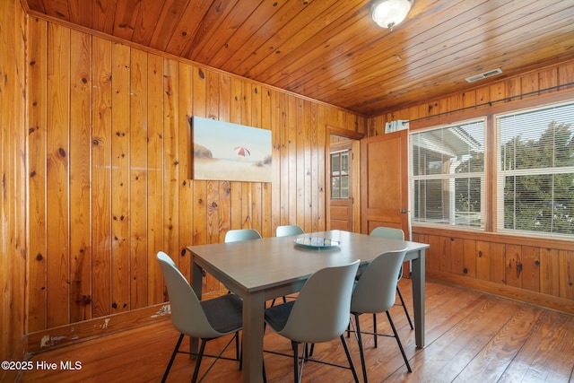 dining area with wood ceiling, wooden walls, and light hardwood / wood-style floors