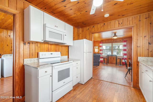 kitchen featuring washer / dryer, white cabinets, light stone countertops, white appliances, and light hardwood / wood-style flooring