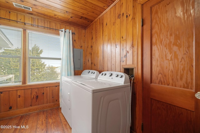 laundry area featuring wood ceiling, hardwood / wood-style flooring, wooden walls, electric panel, and washer and dryer