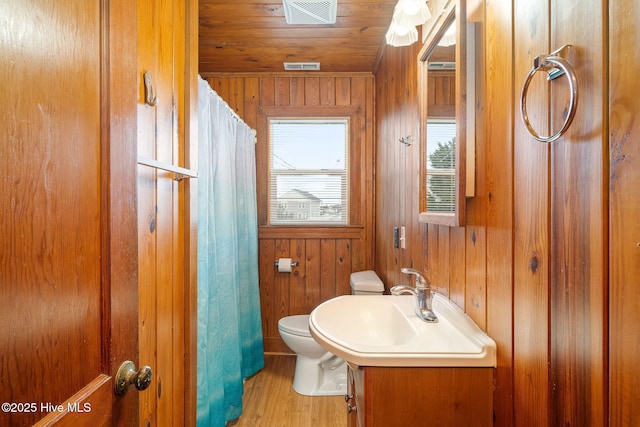 bathroom featuring vanity, wooden walls, wood ceiling, and toilet