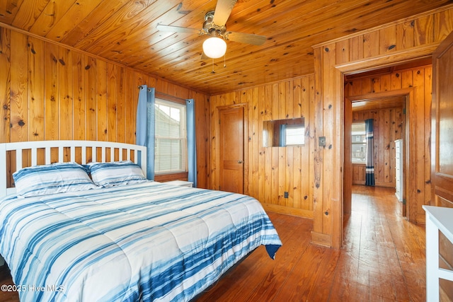 bedroom featuring wood-type flooring, wooden walls, wooden ceiling, and ceiling fan