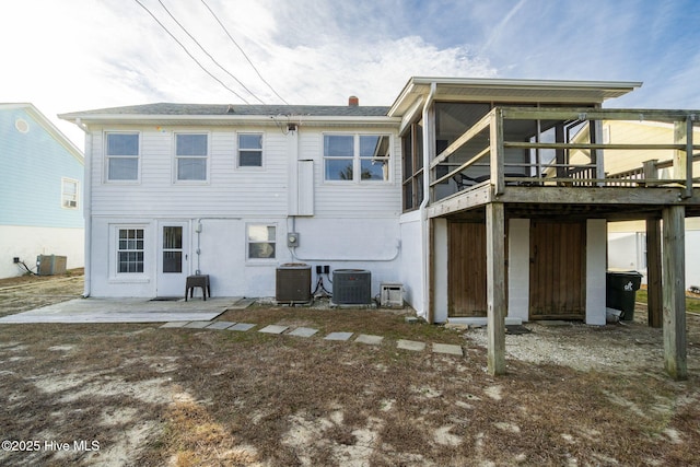 rear view of house with cooling unit, a sunroom, and a patio area