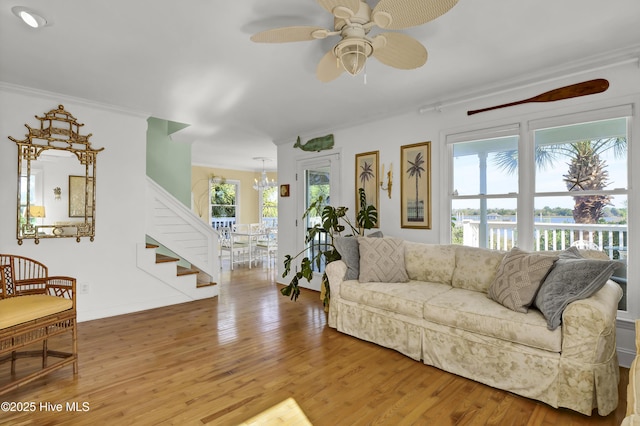 living room with crown molding, plenty of natural light, ceiling fan with notable chandelier, and hardwood / wood-style floors